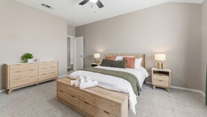 A bedroom with a bed, bedside tables, a ceiling fan, and a door. - Lake Haven Retreat - Spacious 3BR Family Escape Near Lake Lewisville (Little Elm)