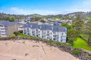 A coastal hotel with multiple floors, a beach view, and a stone wall separating the beach from the property. - Dock of the Bay Condo, Fireplace & Bay Views (Lincoln City)