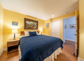 A bedroom with a bed, nightstands, a painting, and a door. - Dock of the Bay Condo, Fireplace & Bay Views (Lincoln City)