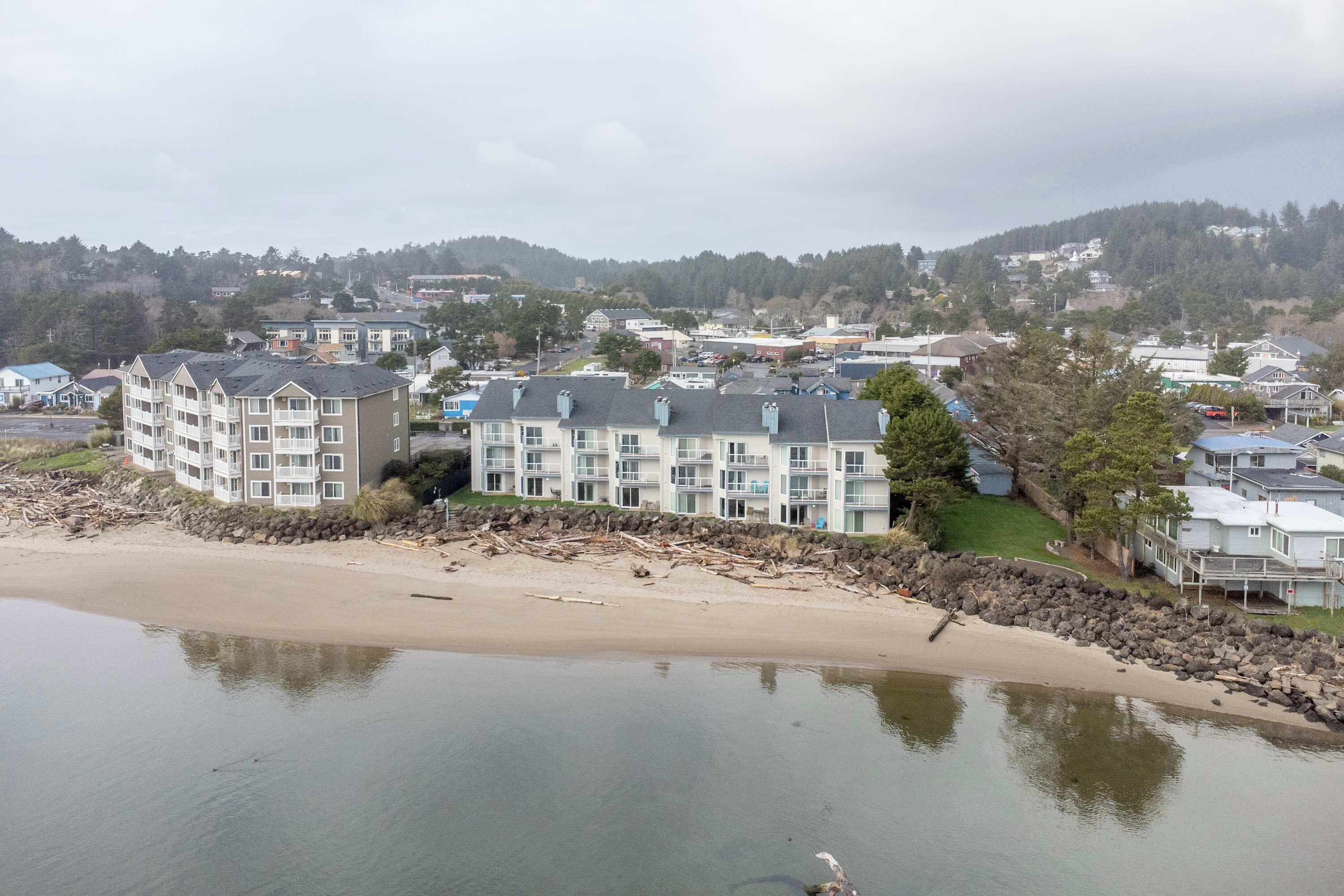 A coastal hotel with multiple floors, a beach view, and a rocky shoreline.
