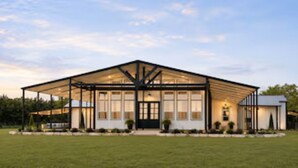 A modern building with a large covered patio, a central entrance, and a symmetrical facade.