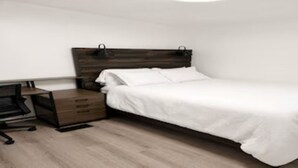 A bedroom with a bed, a desk, and a chair.