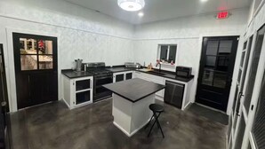 A modern kitchen with a central island, black countertops, white cabinetry, and a ceiling light fixture.