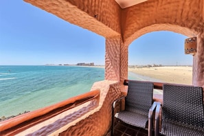 Ein Balkon mit Korbstühlen mit Blick auf Strand und Meer.