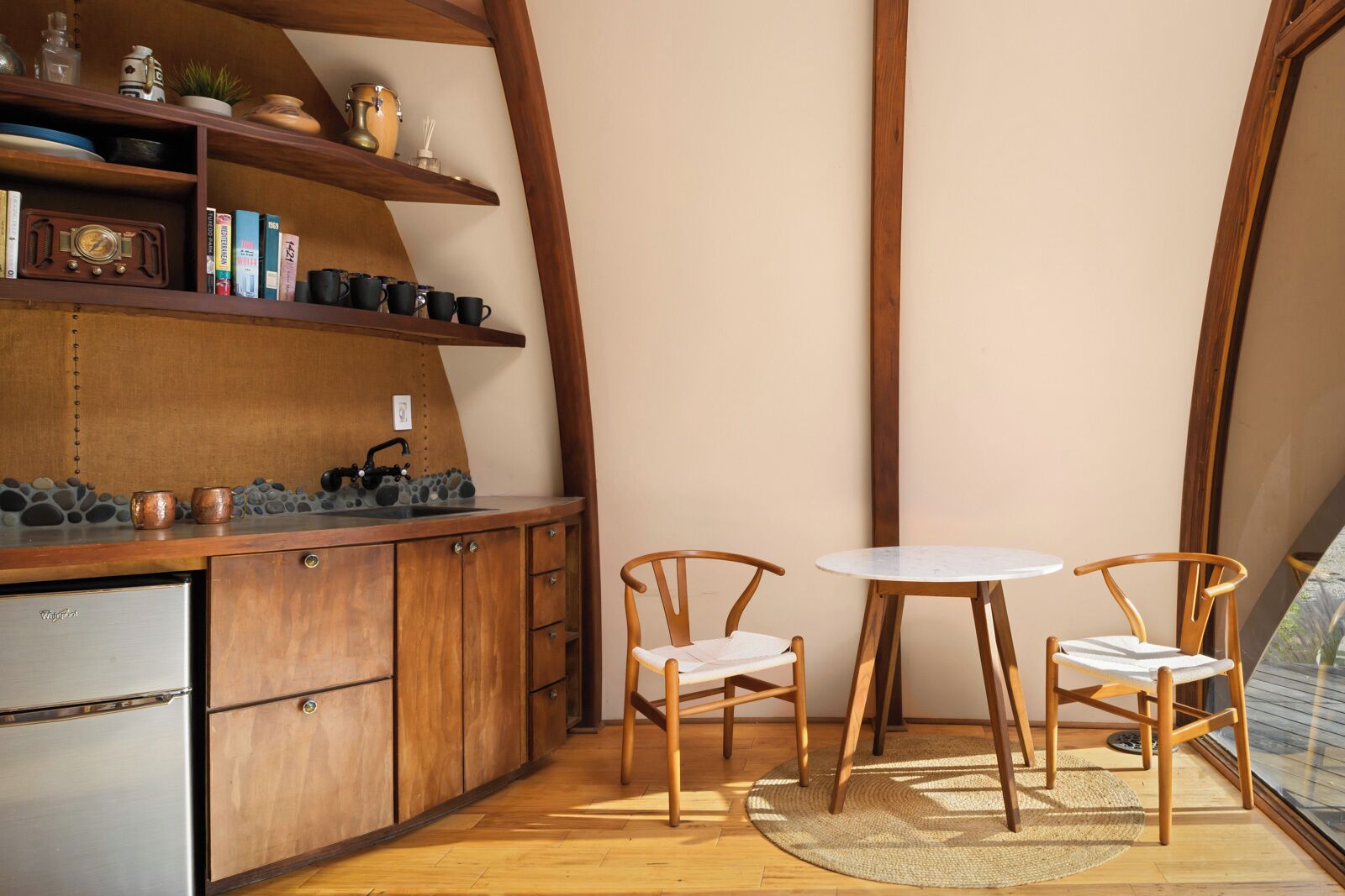 Una cocina acogedora con armarios de madera, estufa empotrada y una mesa redonda con dos sillas.