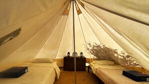 Una carpa con dos camas, una mesa central con un farol y un ventilador.