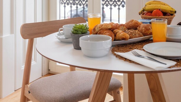 Una mesa de desayuno con cruasanes, una banana y jugo de naranja.