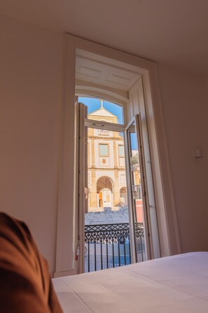 Une porte ouverte donnant sur un balcon d’où l’on peut admirer un bâtiment historique.