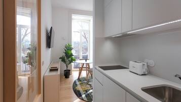 Une cuisine moderne avec des meubles blancs, un évier en acier inoxydable, un grille-pain et une plante en pot.
