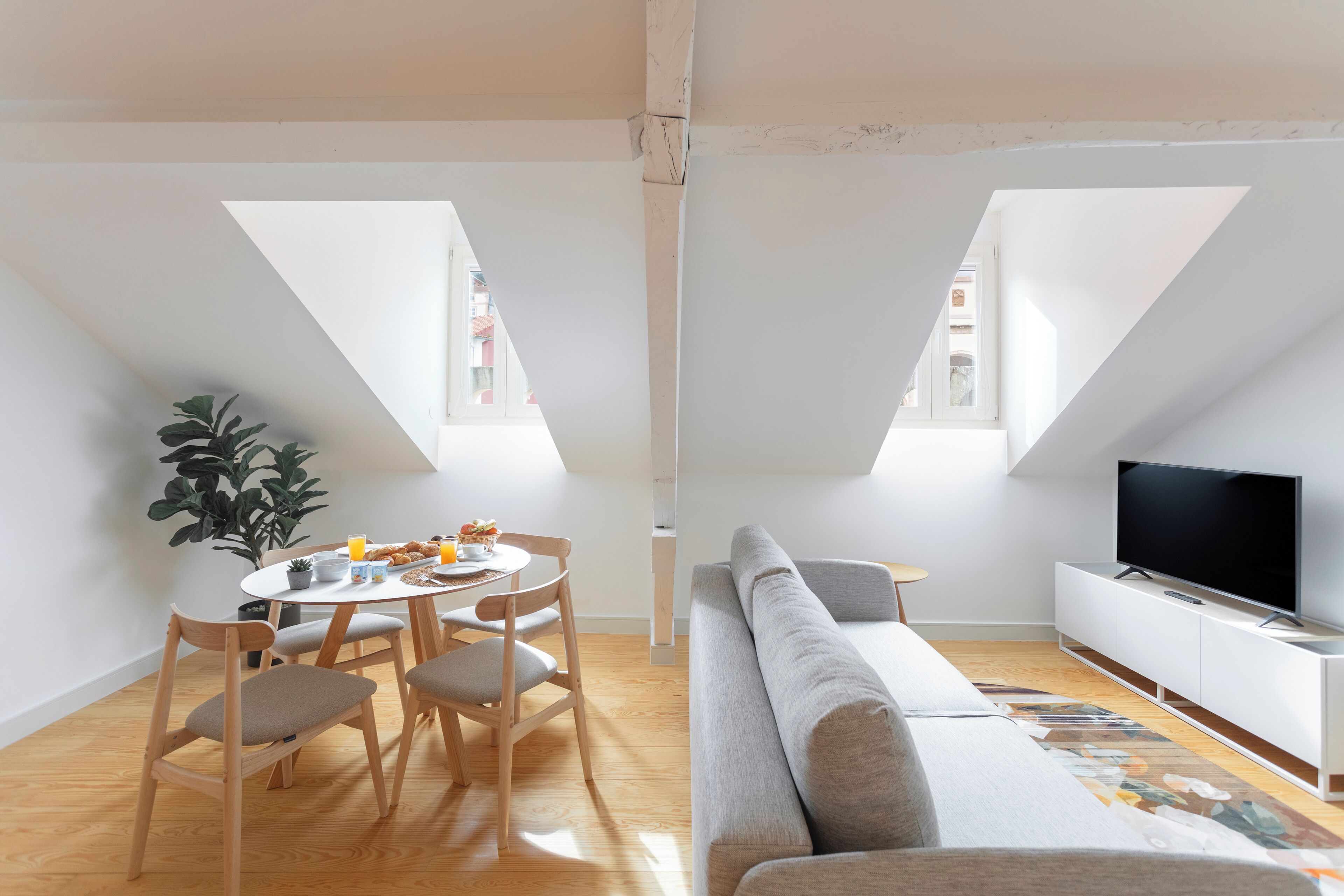 Un interior con comedor, sofá, televisor y planta.