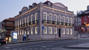 Un edificio histórico con un balcón, un letrero que indica una zona de estacionamiento y vista a la calle.