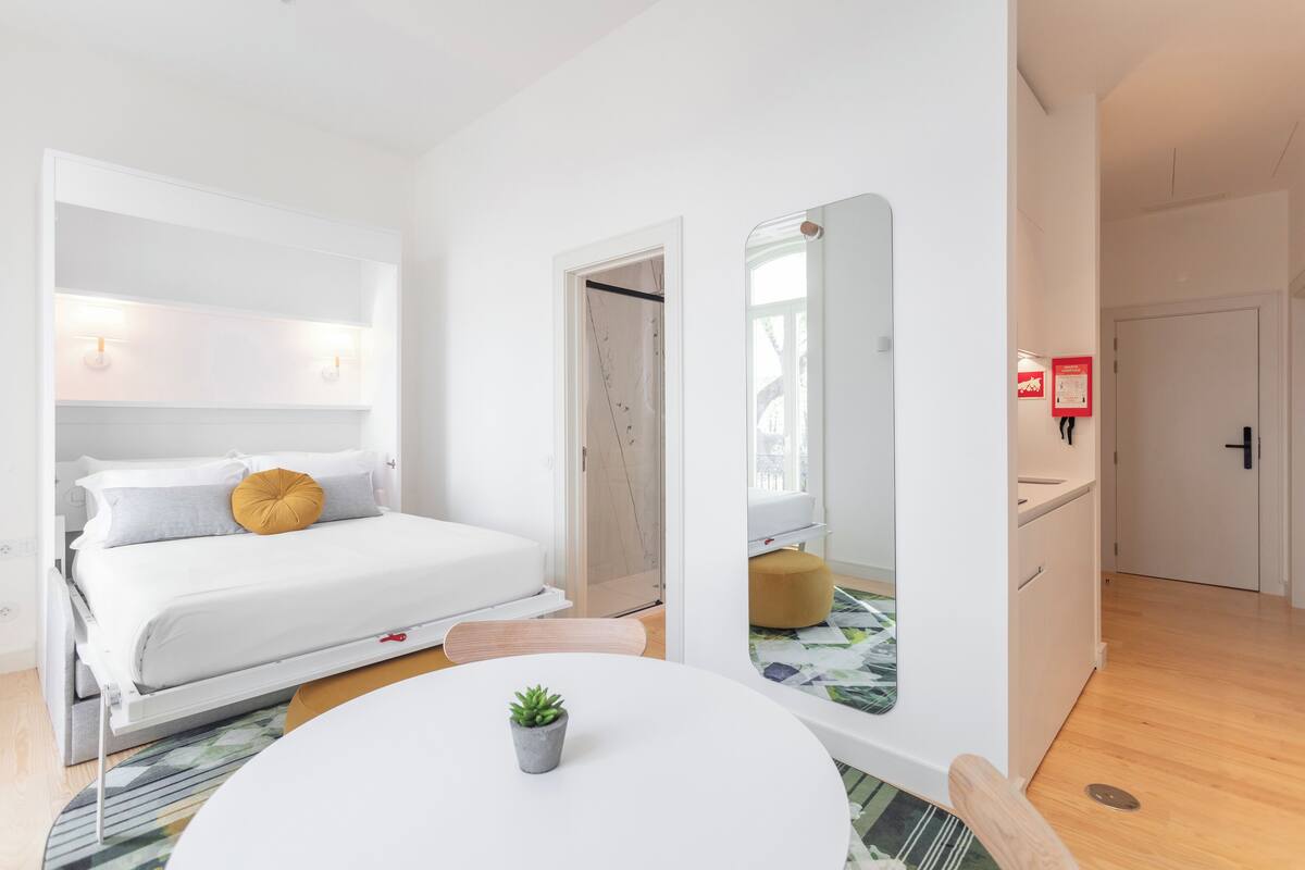 A modern bedroom with a bed, bedside table, and a small potted plant.