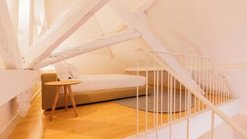 A bedroom with a bed, a small table, and a staircase.