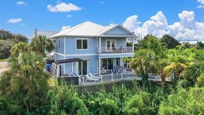Une maison à deux étages dotée d’un balcon, entourée d’une végétation luxuriante.