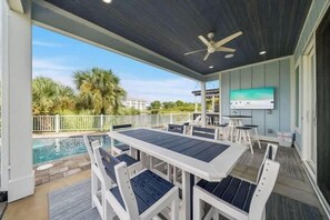 Une terrasse extérieure avec une piscine, un ventilateur de plafond et un écran de télévision.