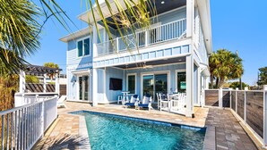 Ein zweistöckiges Haus mit Pool, Gartenmöbeln und einer überdachten Terrasse.