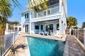 A two-story house with a pool, outdoor furniture, and a covered patio area. - Stunning custom coastal hideaway with private pool (Panama City Beach)