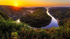 A river valley with a road curving through it, surrounded by dense forest. - Vacation apartment - Cozy apartment in the Saarland (Losheim am See)