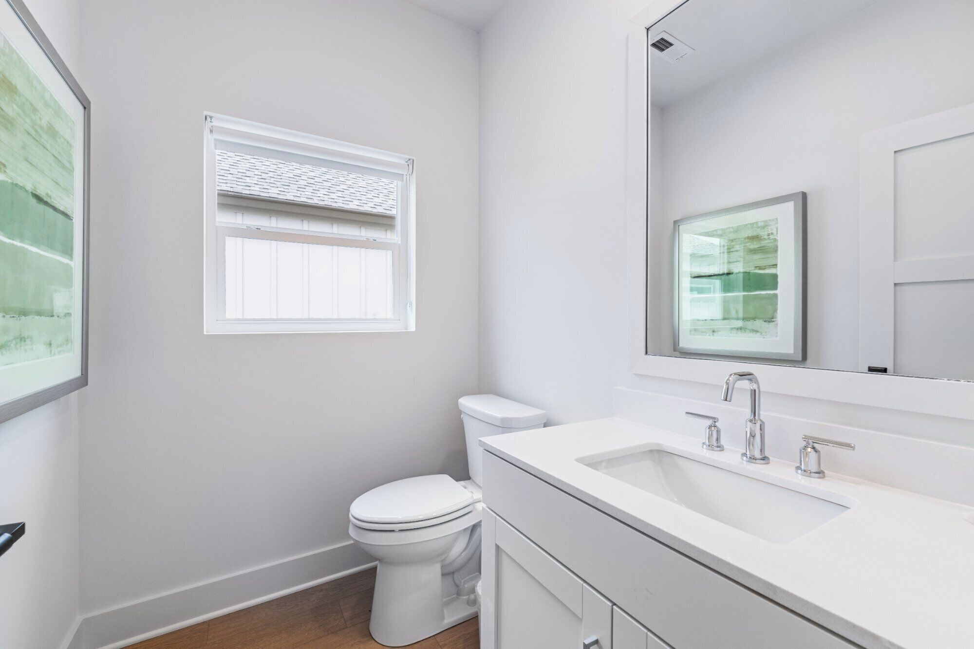 A modern bathroom with a toilet, a sink, and a window with blinds.