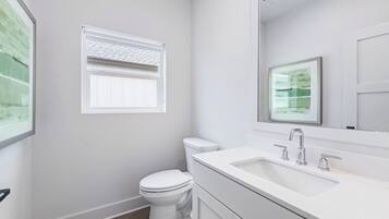 A modern bathroom with a toilet, a sink, and a window with blinds.