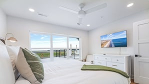 Ein Schlafzimmer mit einem großen Bett, einem an der Wand montierten Fernseher und einem Balkon mit Blick.