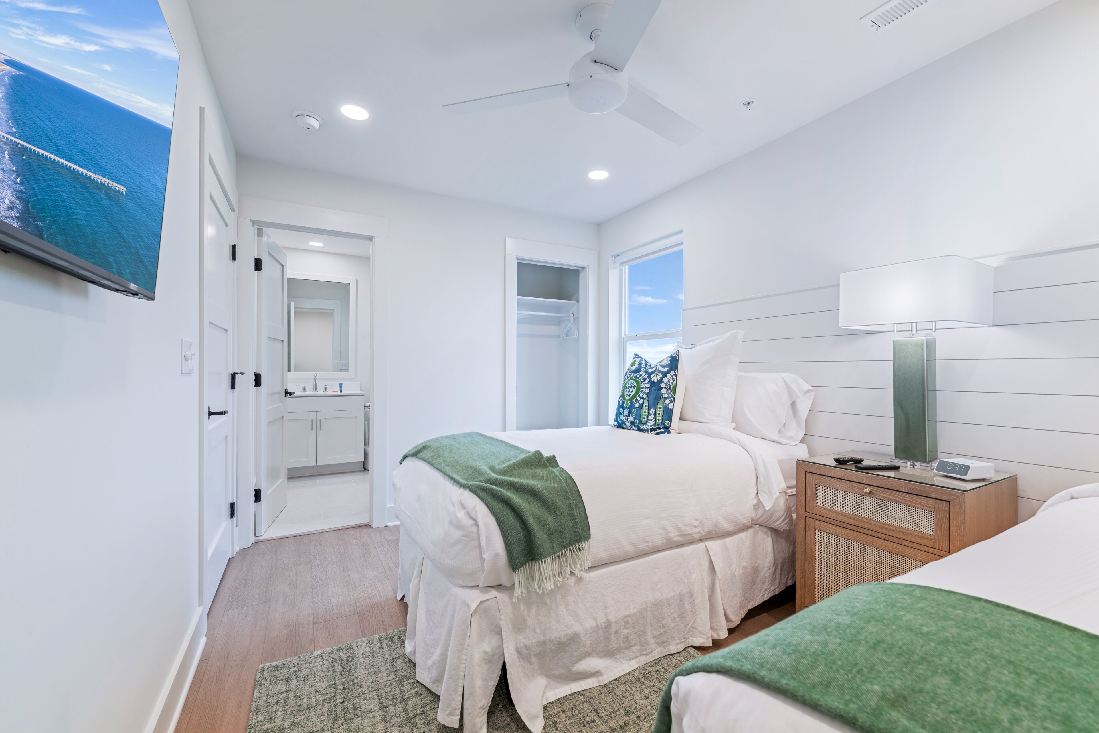 A bedroom with a bed, bedside table, lamp, and a TV mounted on the wall.