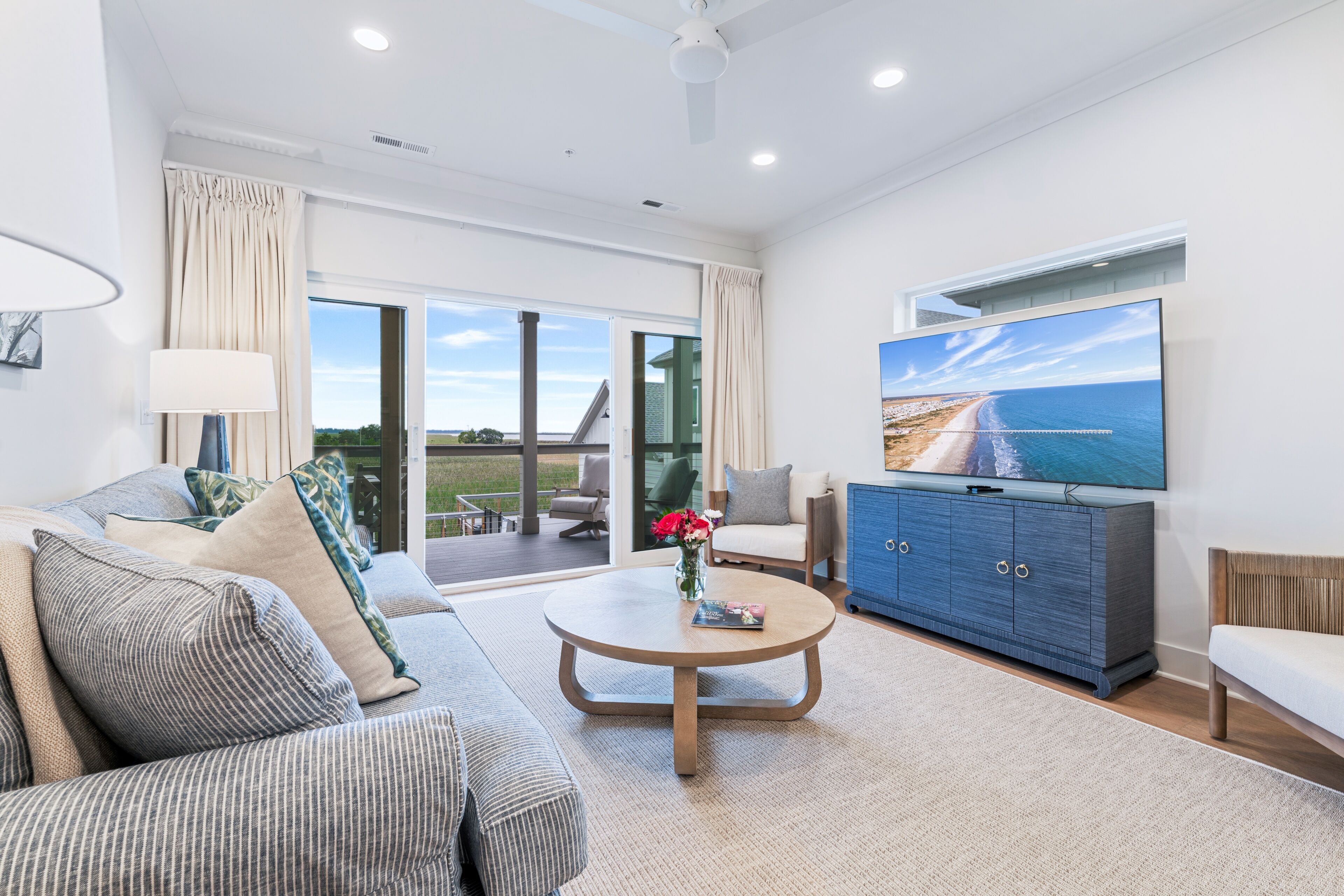 A modern living room with a sofa, coffee table, TV, and a view of the outdoors.