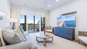 A modern living room with a sofa, coffee table, TV, and a view of the outdoors.