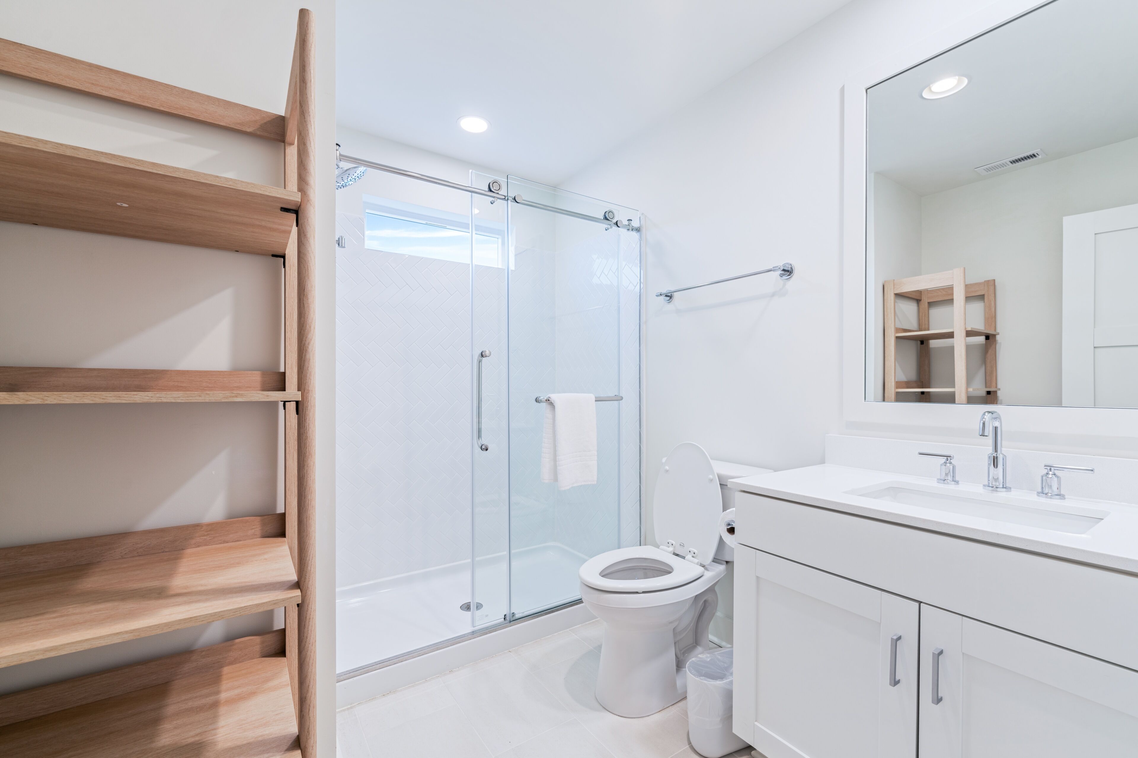 Une salle de bain moderne avec une douche à parois de verre, des toilettes, un lavabo et un miroir.