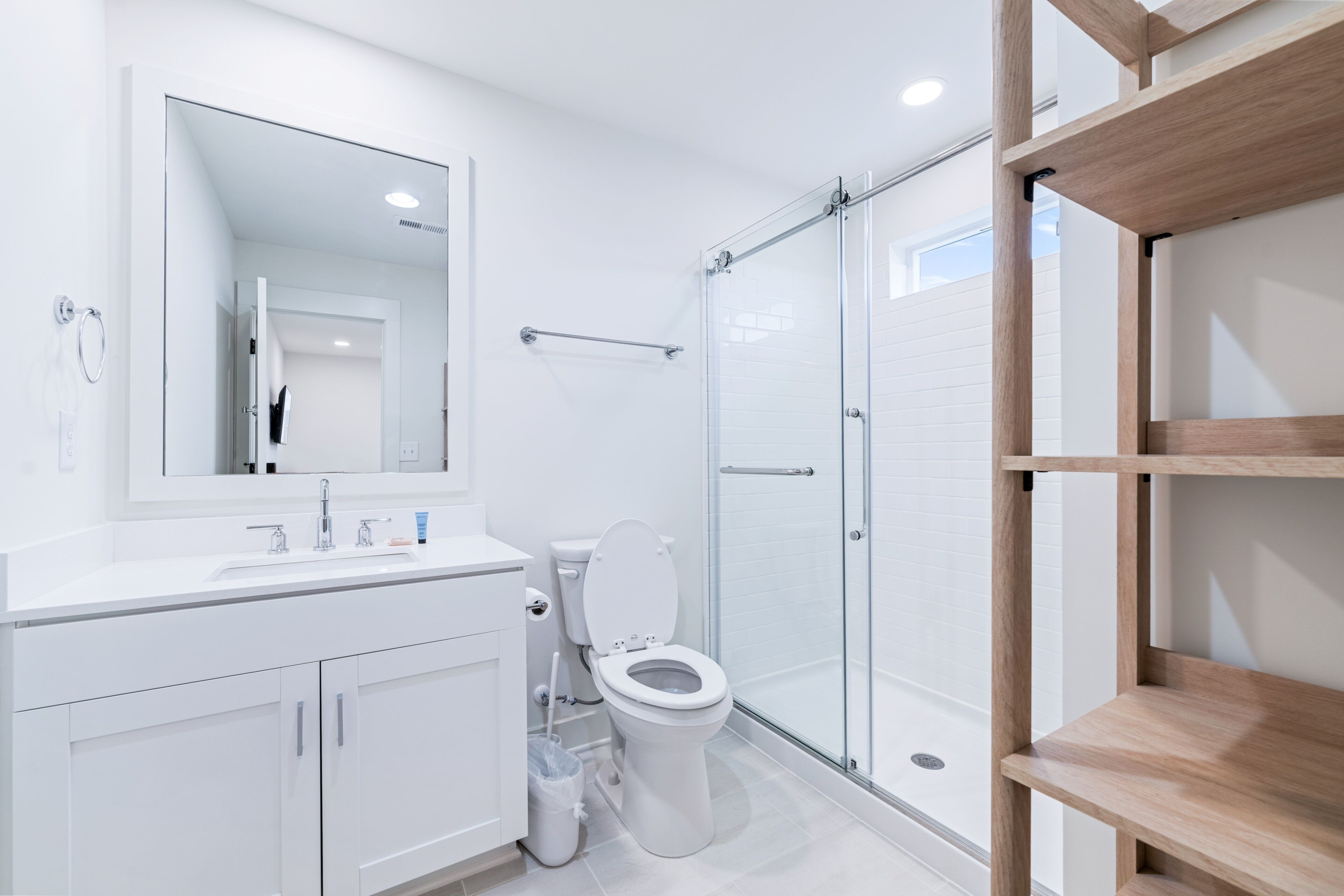 A modern bathroom with a glass shower enclosure, a white sink, and a toilet.