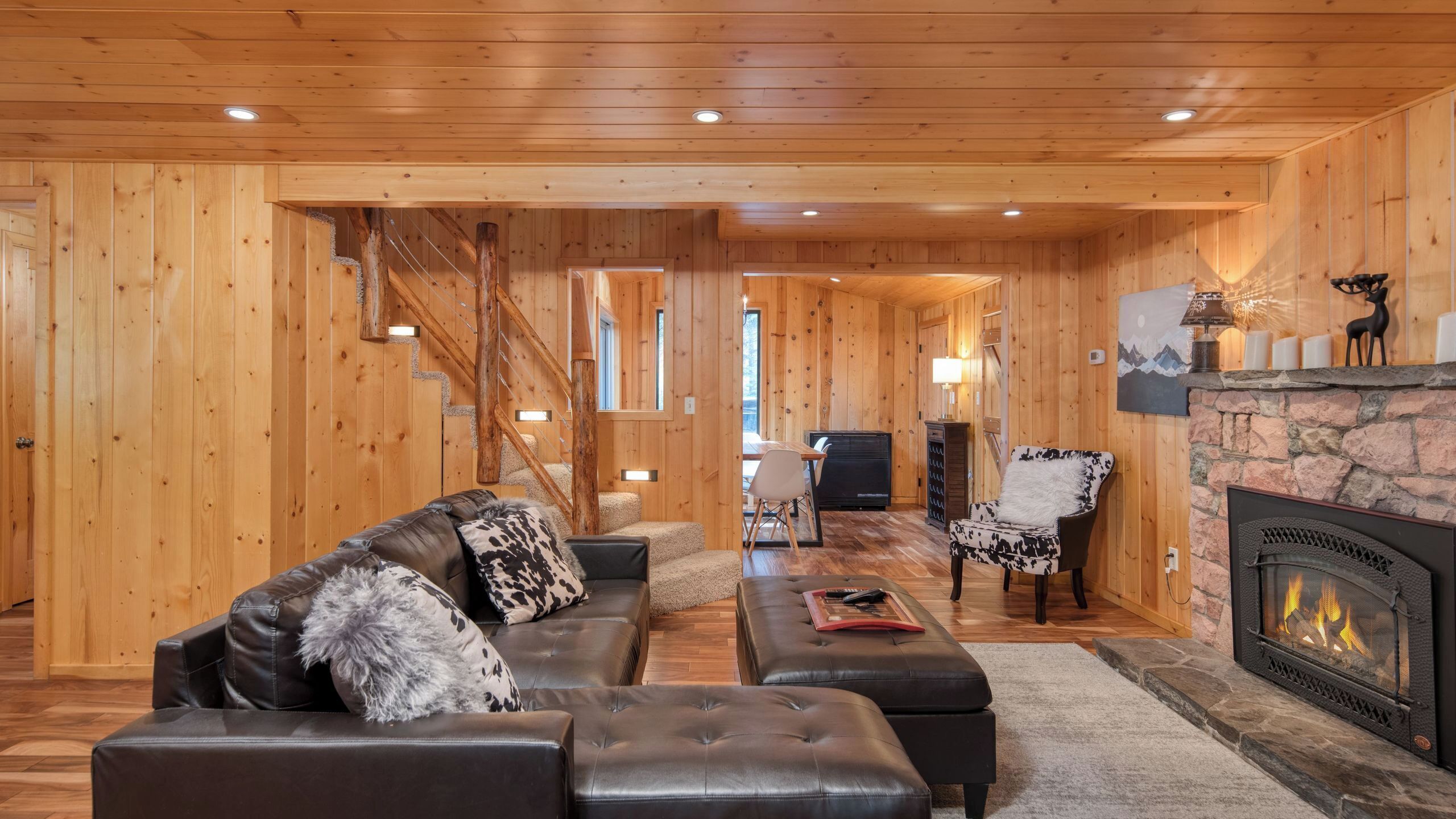 Ein Blockhaus-Interieur mit Kamin, Ledersofa und einem Kamin ummantelt mit Stein.