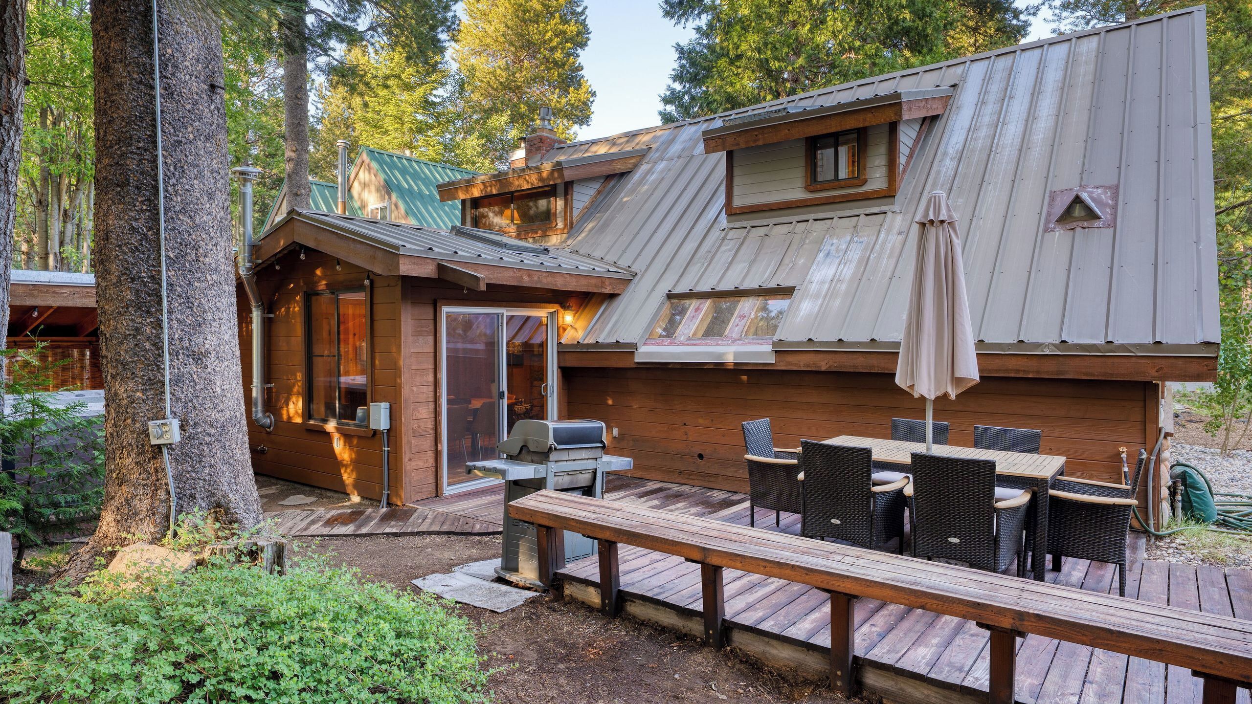 A cabin with a deck, outdoor seating, and a chimney.