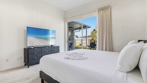 Quarto com cama, televisão, penteadeira e vista para o exterior.