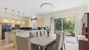 Uma cozinha moderna com ilha central, iluminação pendente e vista para o exterior.