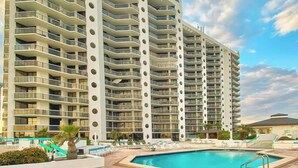 Un hotel moderno de altura con varios balcones, piscina y sillas de descanso.