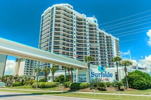 Un hôtel de grande hauteur, reconnaissable à son grand panneau indiquant « Surfside Resort », doté de nombreux balcons et d’une passerelle couverte.
