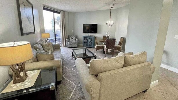 A living room with a sofa, armchair, coffee table, and a television. - Charming condo, with shared pool, Gym, and Tennis (Miramar Beach)
