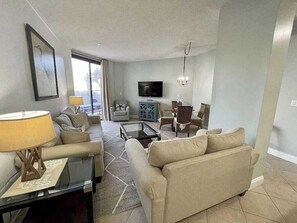 A living room with a sofa, armchair, coffee table, and a television. - Charming condo, with shared pool, Gym, and Tennis (Miramar Beach)