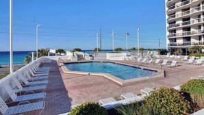 A pool area with lounge chairs, a swimming pool, and a view of the ocean. - Charming condo, with shared pool, Gym, and Tennis (Miramar Beach)