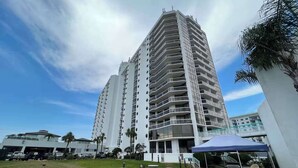 A high-rise building with multiple balconies, outdoor seating, and a covered barbecue area. - Charming condo, with shared pool, Gym, and Tennis (Miramar Beach)