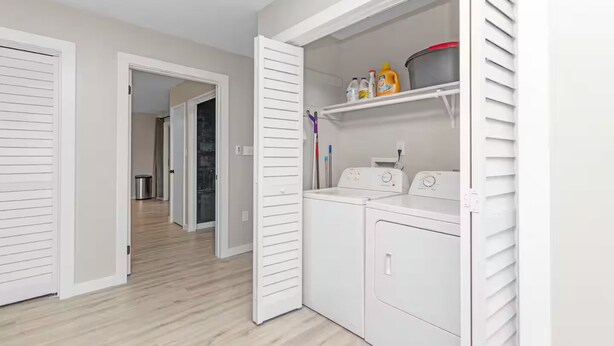 Un espace buanderie comprenant un lave-linge et un sèche-linge, une étagère avec des produits de nettoyage et une porte donnant sur une autre pièce.