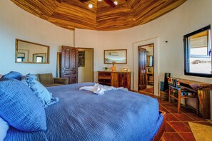 Ein Schlafzimmer mit einem großen Bett, Holzboden und einem Schreibtisch mit Stuhl.