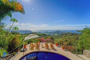 Uma piscina com espreguiçadeiras e vista para a paisagem.