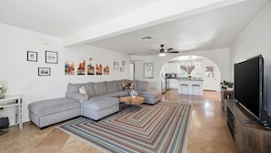 A living room with a sectional sofa, a flat-screen TV, and artwork on the walls.