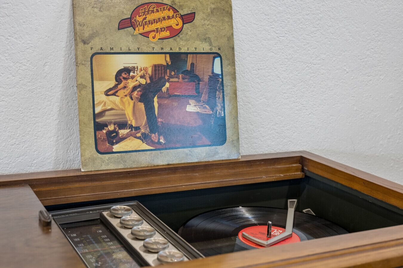 Un juke-box con un tocadiscos, un cartel en la pared y un mueble de madera.