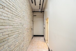 Un couloir étroit aux murs en briques apparentes et au sol carrelé.