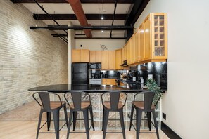 Une cuisine moderne dotée d’un îlot central, de tabourets de bar et de meubles de rangement en bois.