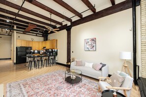 A spacious living area with a sofa, coffee table, and a kitchen in the background. - Open-Concept Loft Exchange District | 1 Bed | 1 Bath | (Winnipeg)