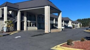Un motel con entrada cubierta, varios pisos y estacionamiento.
