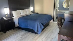 Una habitación de hotel con cama, mesita de noche y cómoda.